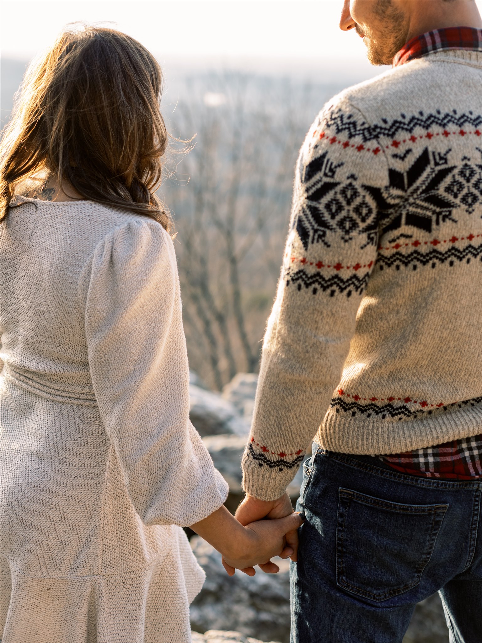 engaged couple holds hands during Christmas inspired engagement photos