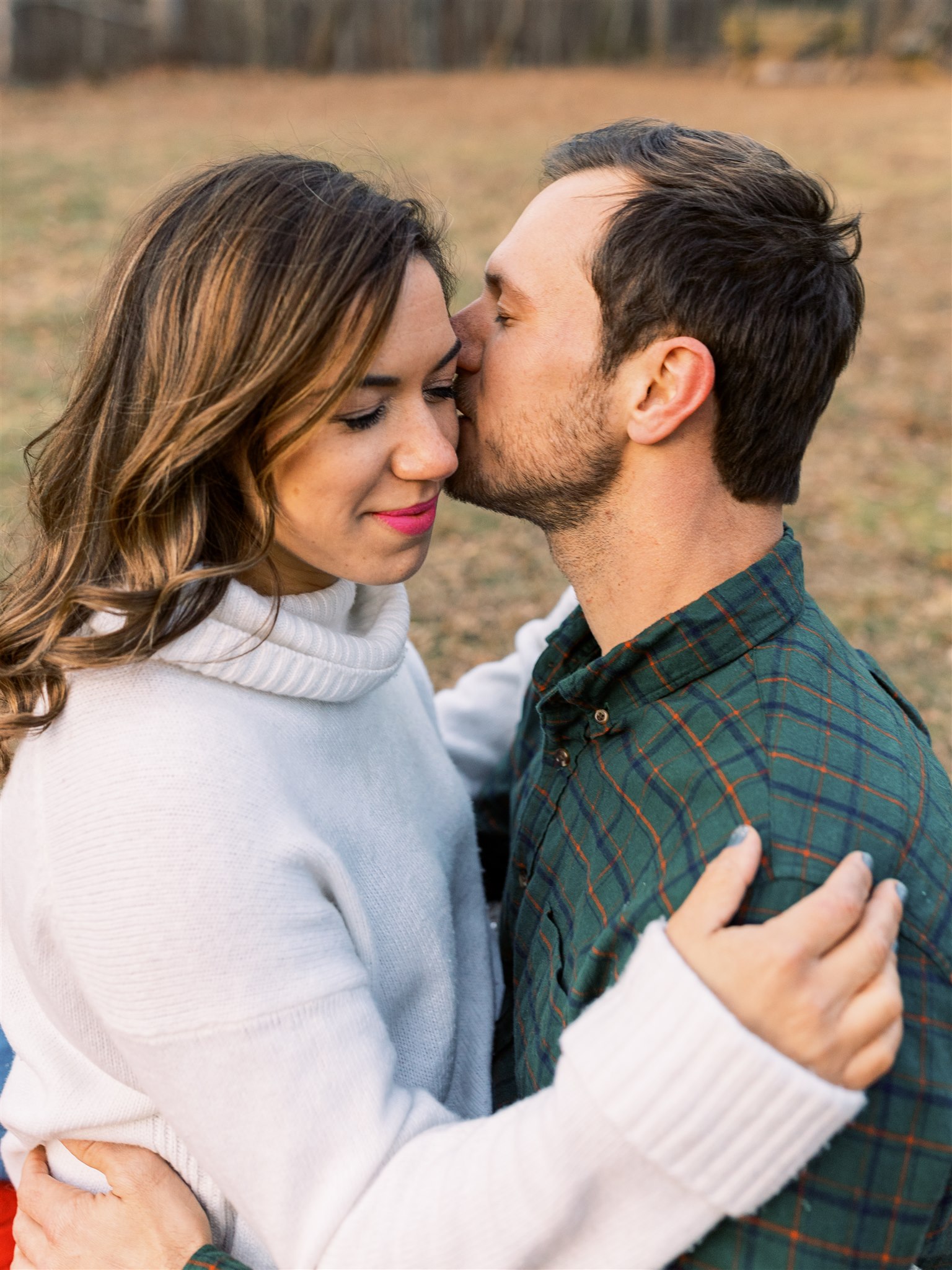 groom kisses bride during cozy winter engagement session