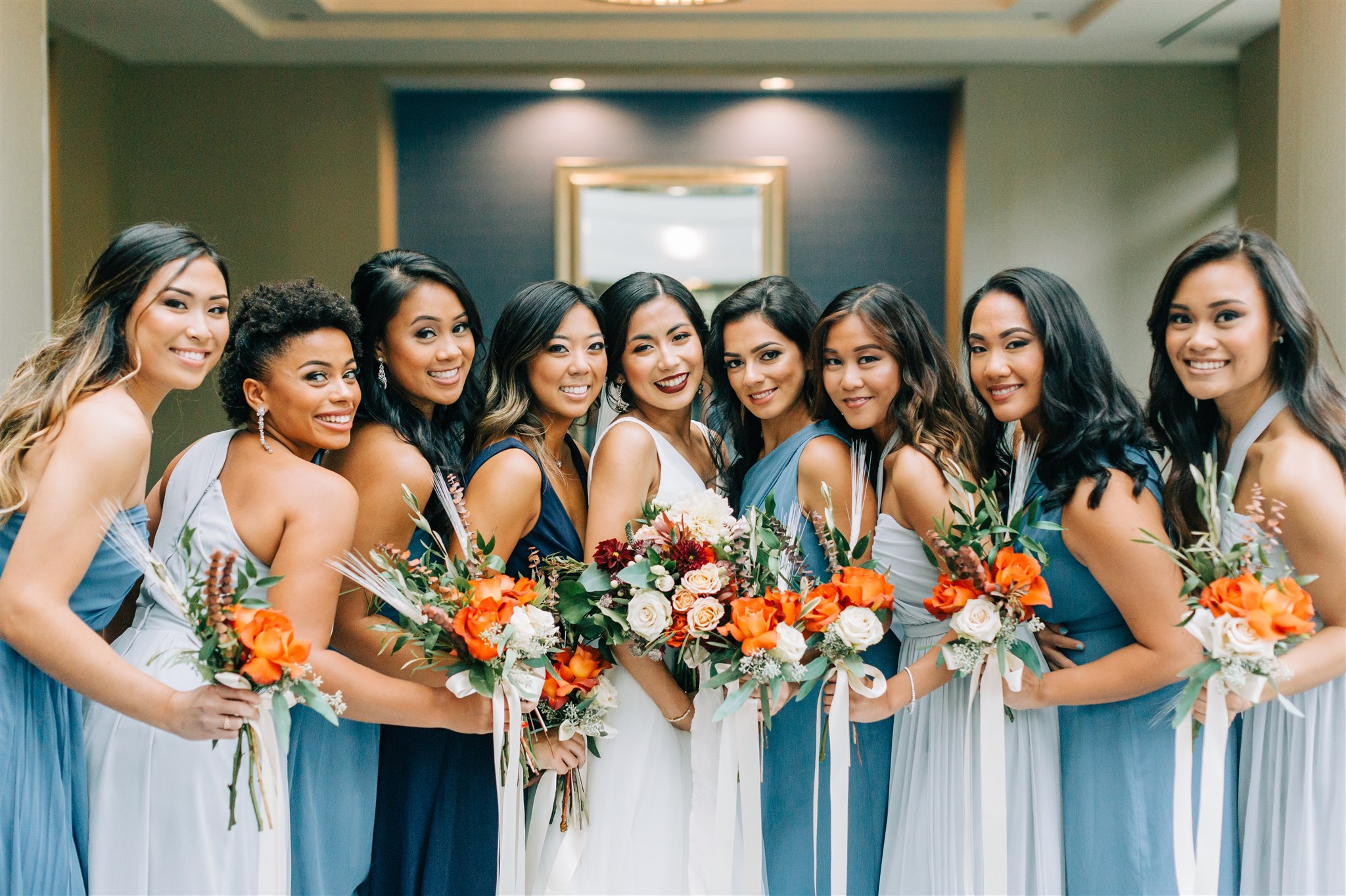 bride and bridesmaids hold bouquet of orange flowers