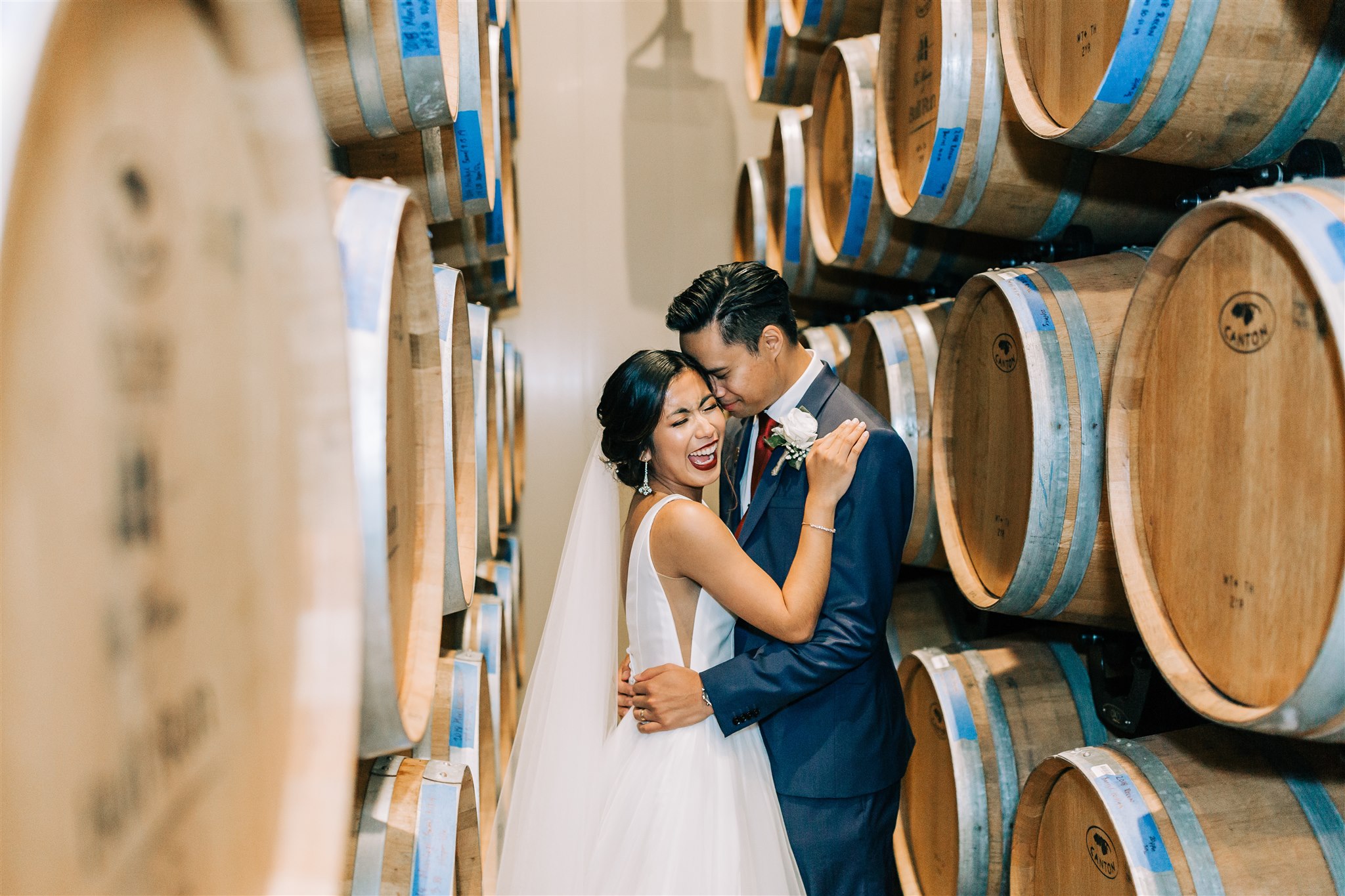 newlyweds kiss among barrels in VA winery
