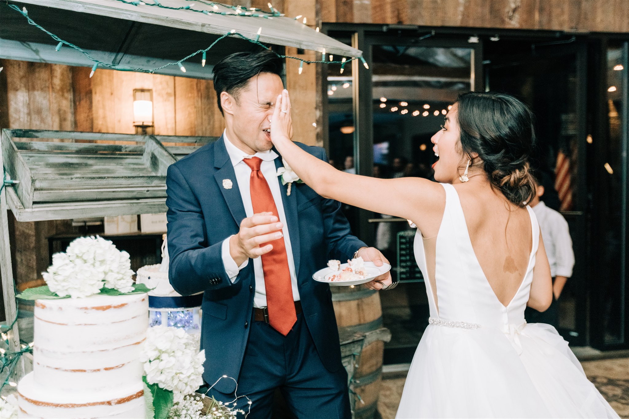 bride smears wedding cake in groom's face