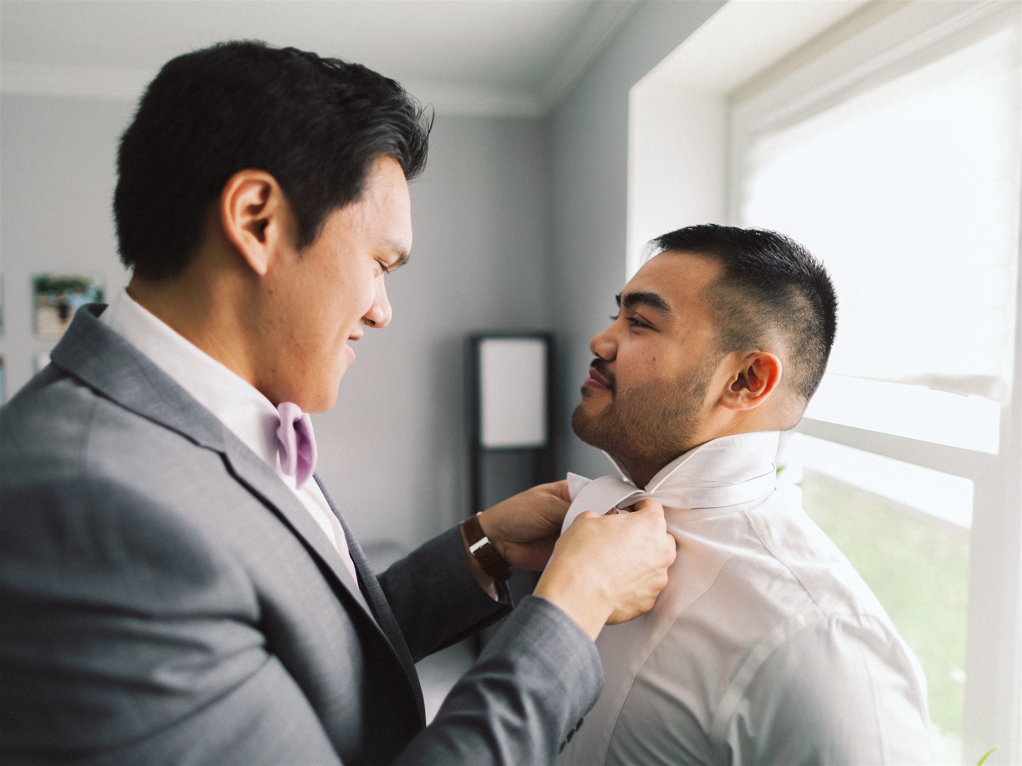 groomsman helps groom with tie
