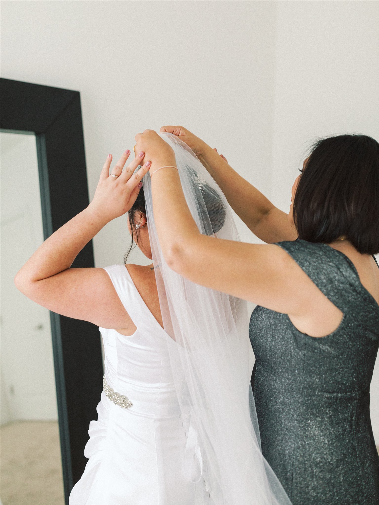 mother of bride helps adjust veil for bride