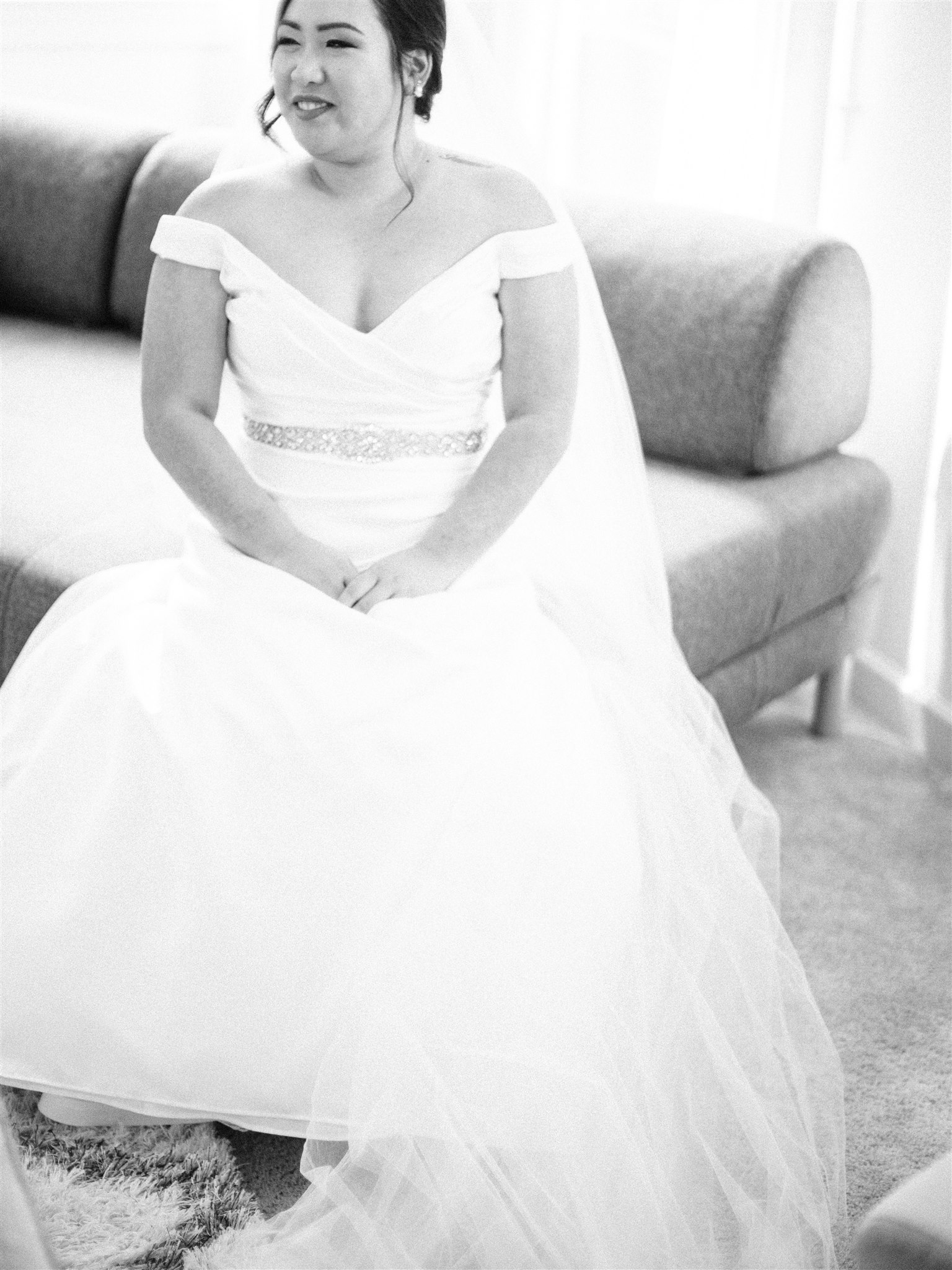 bride in classic off the shoulder gown sits for bridal portrait