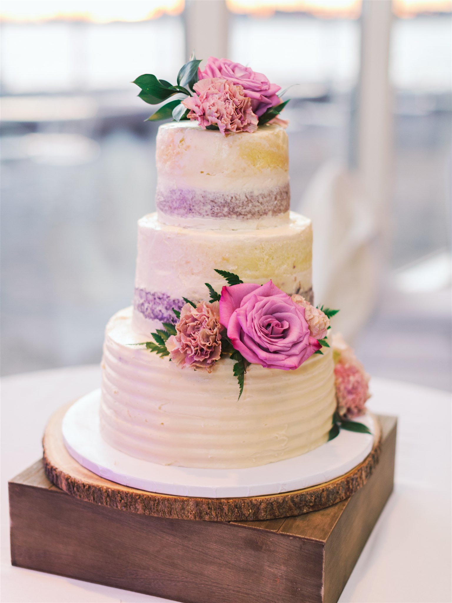 tiered wedding cake with pink and purple flowers