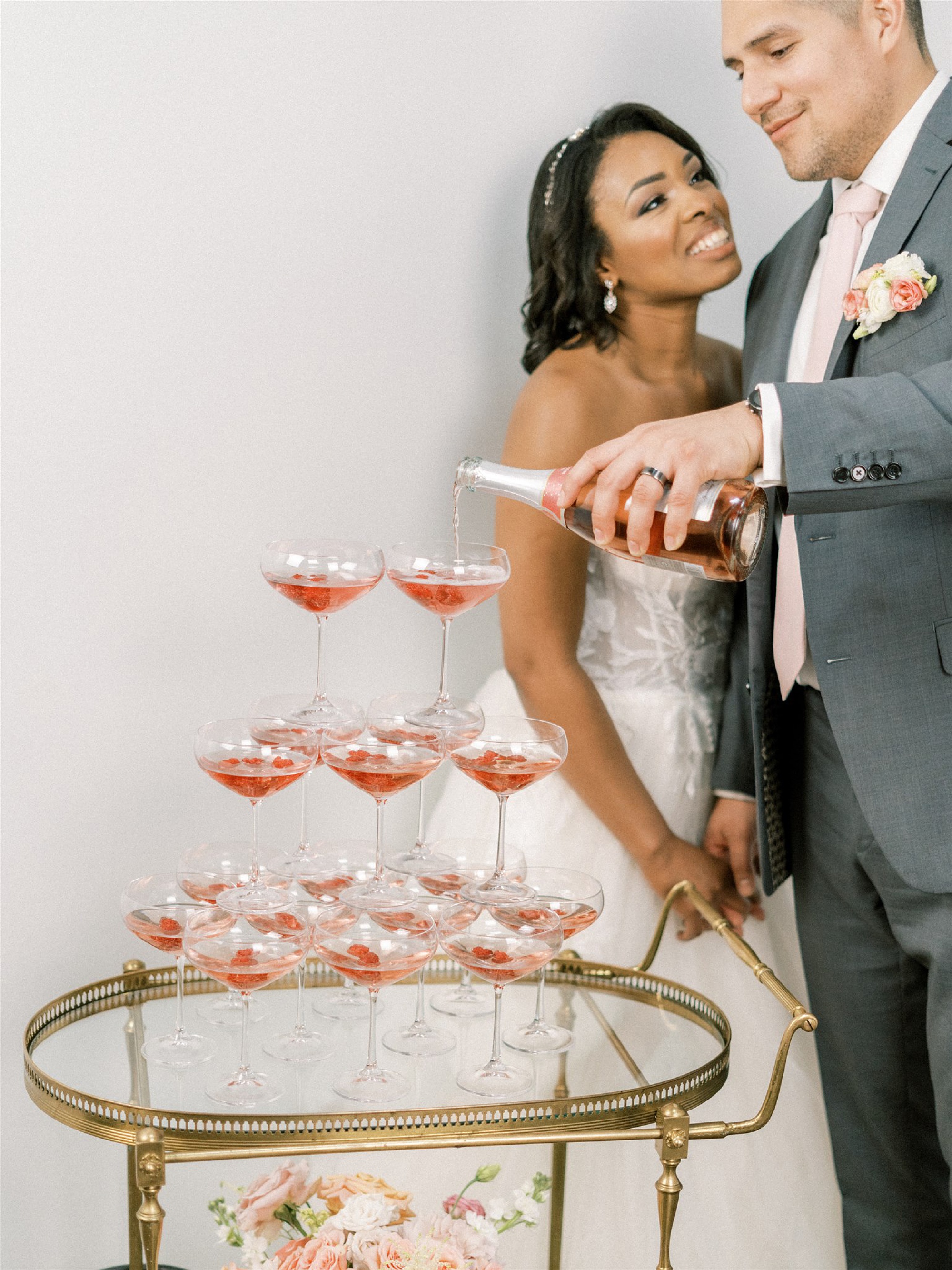 groom pours champagne on tower of glasses