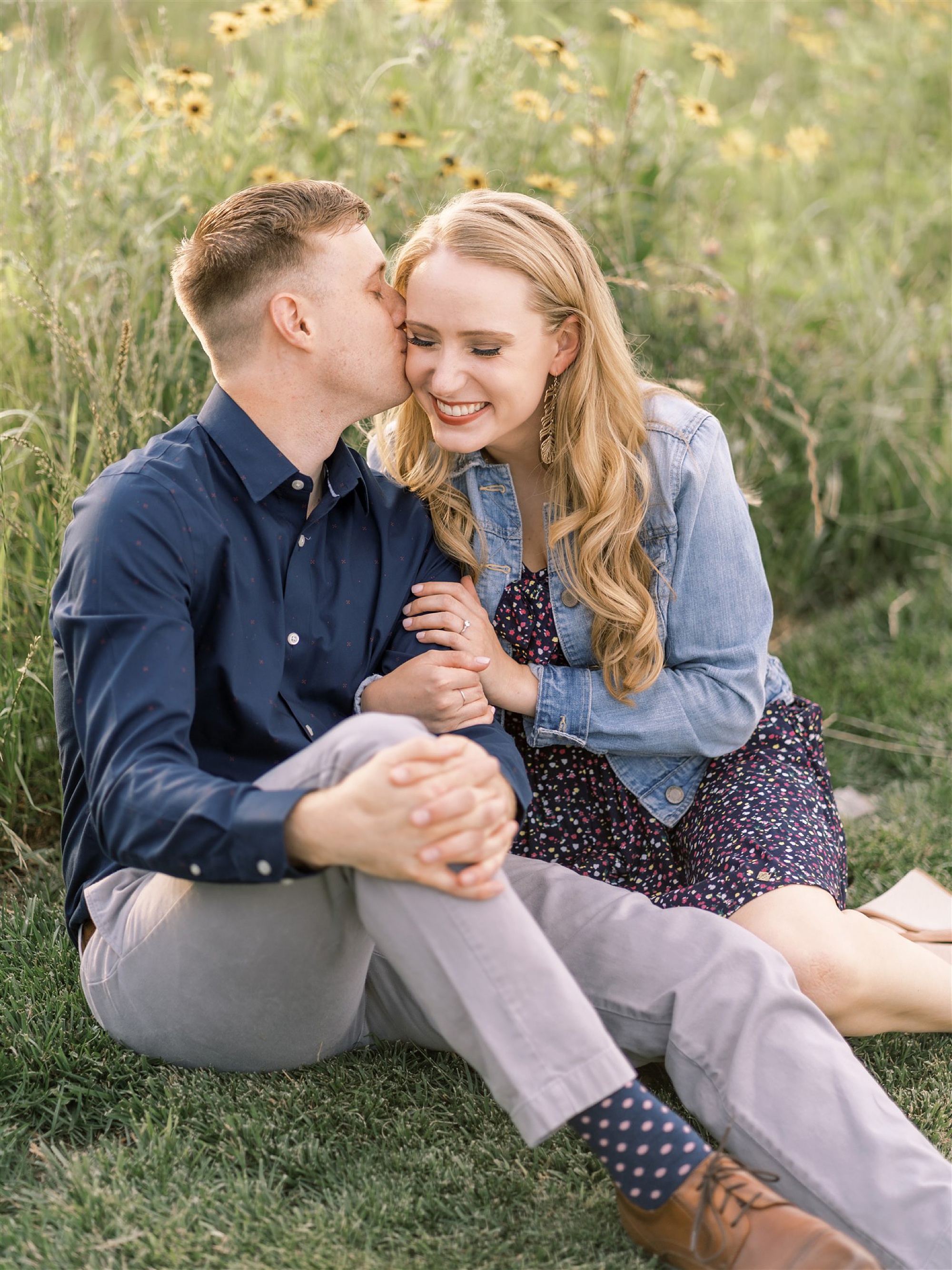 groom whispers in bride's ear during summer engagement portraits