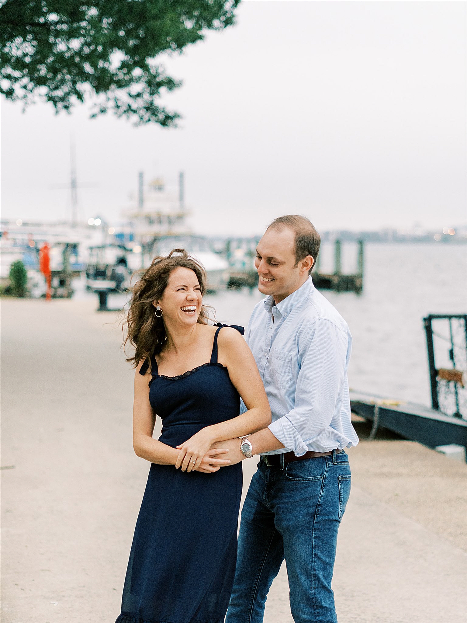 engaged couple laughs on pier at Old Town Alexandria