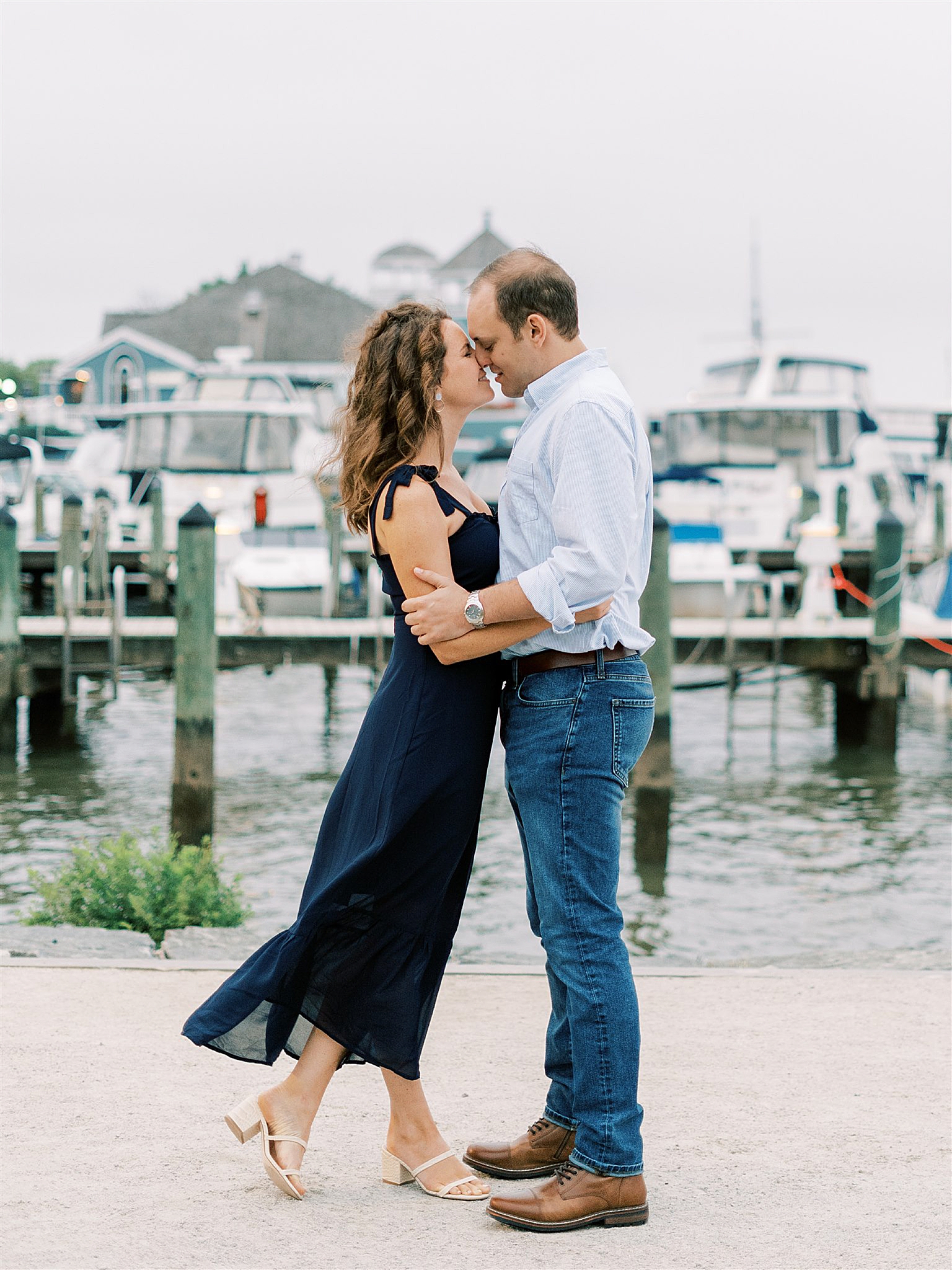 engaged couple poses along Potomac River in Old Town Alexandria