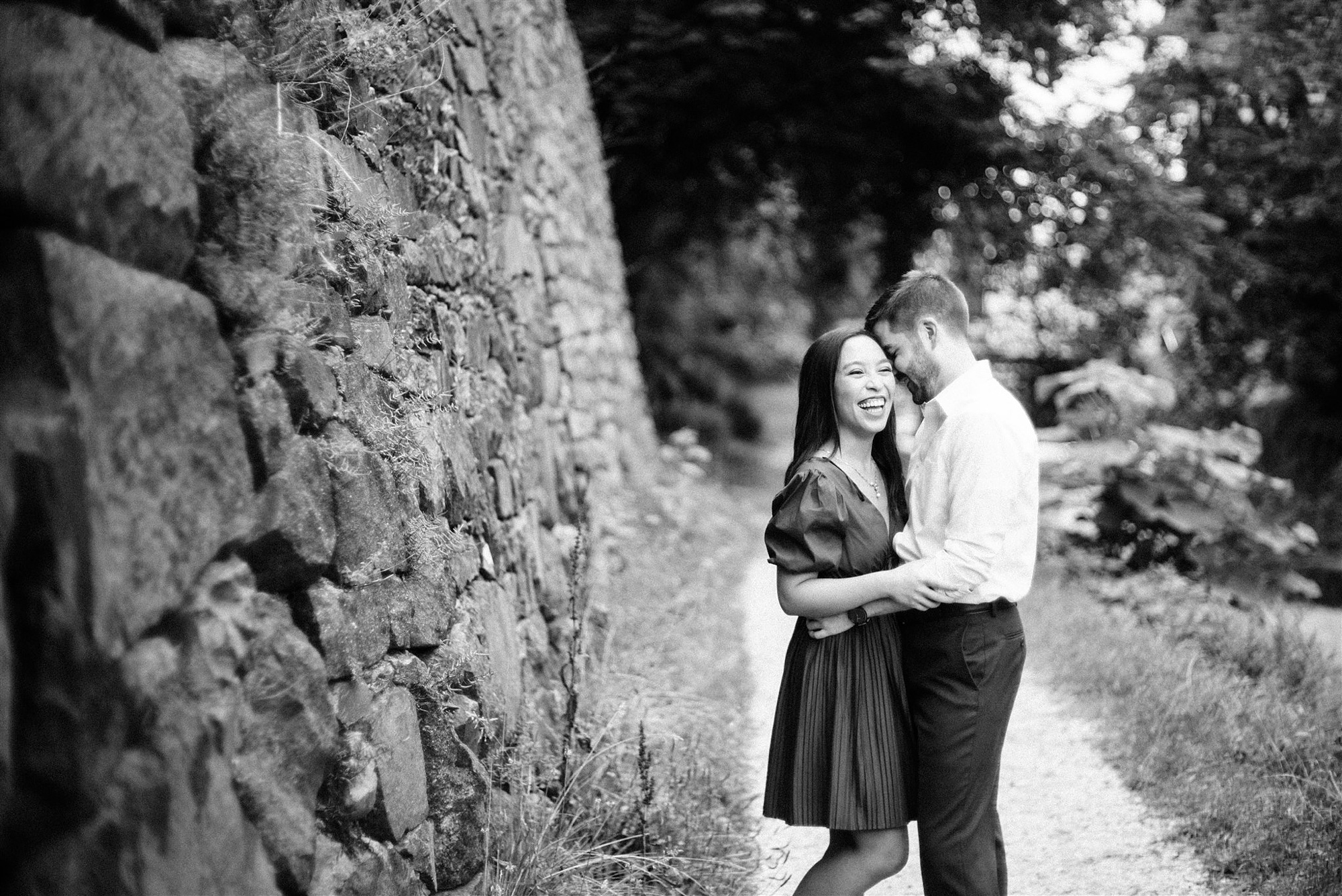 engaged couple stand near wall at canal laughing during Georgetown DC Engagement Session