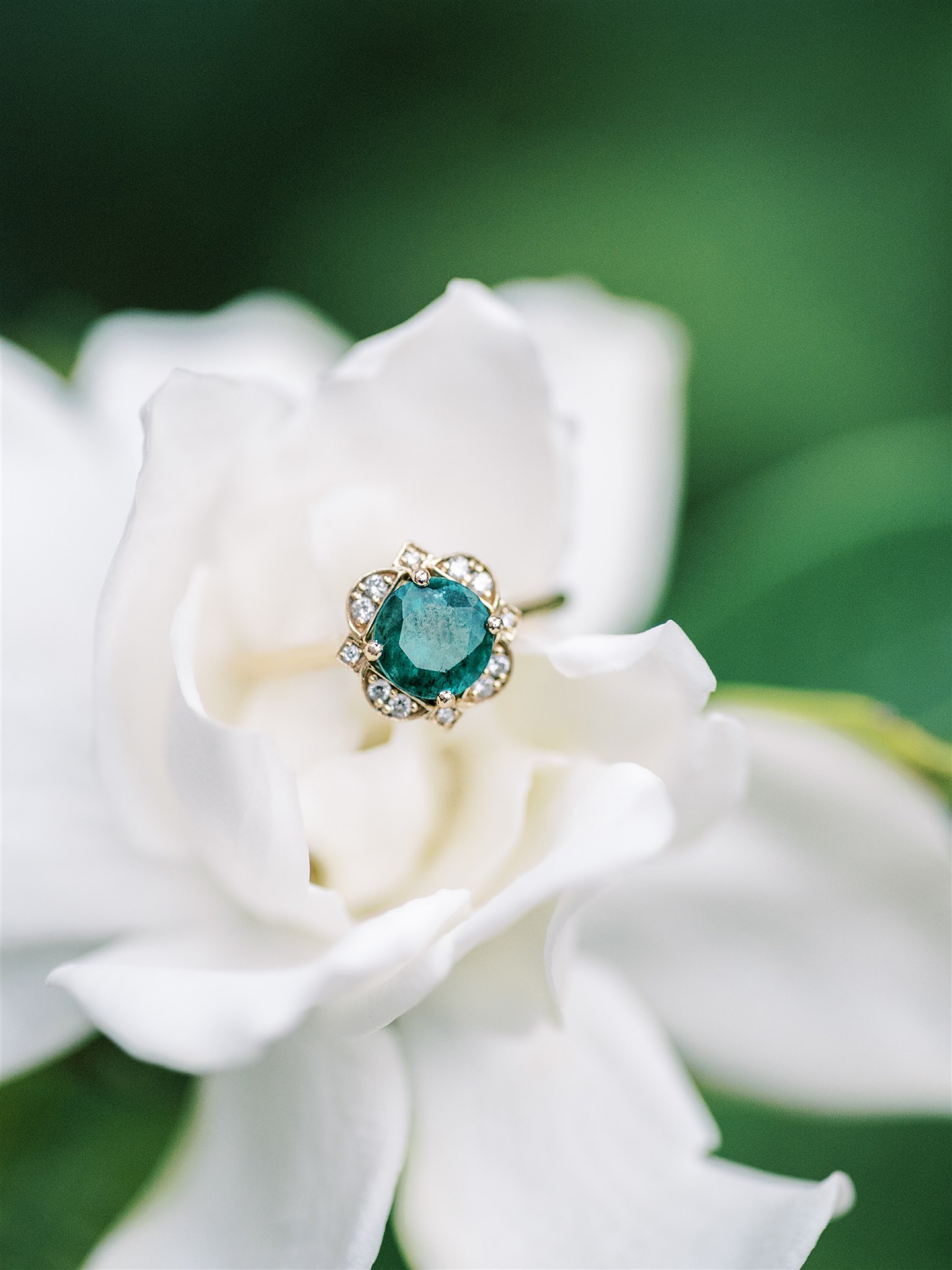 engagement ring with green stone rests on white flower in Norfolk VA