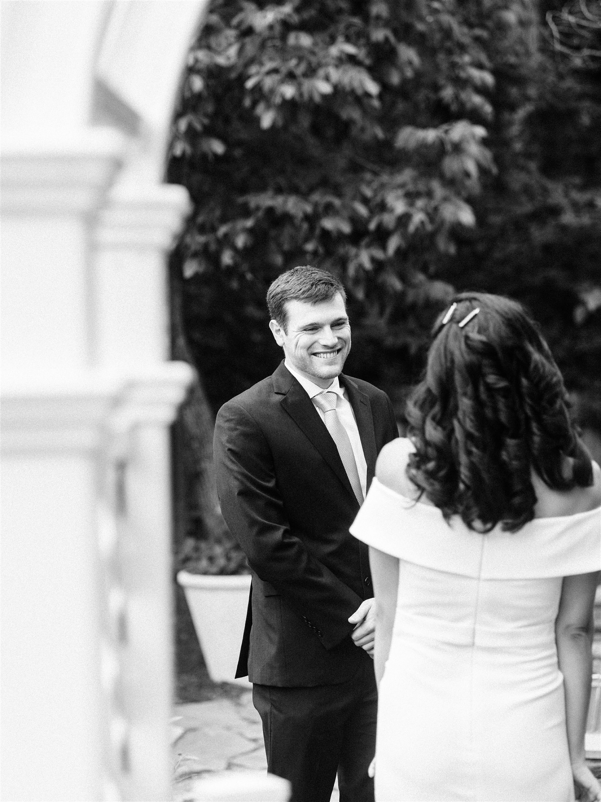 groom smiles at bride during first look before intimate backyard wedding