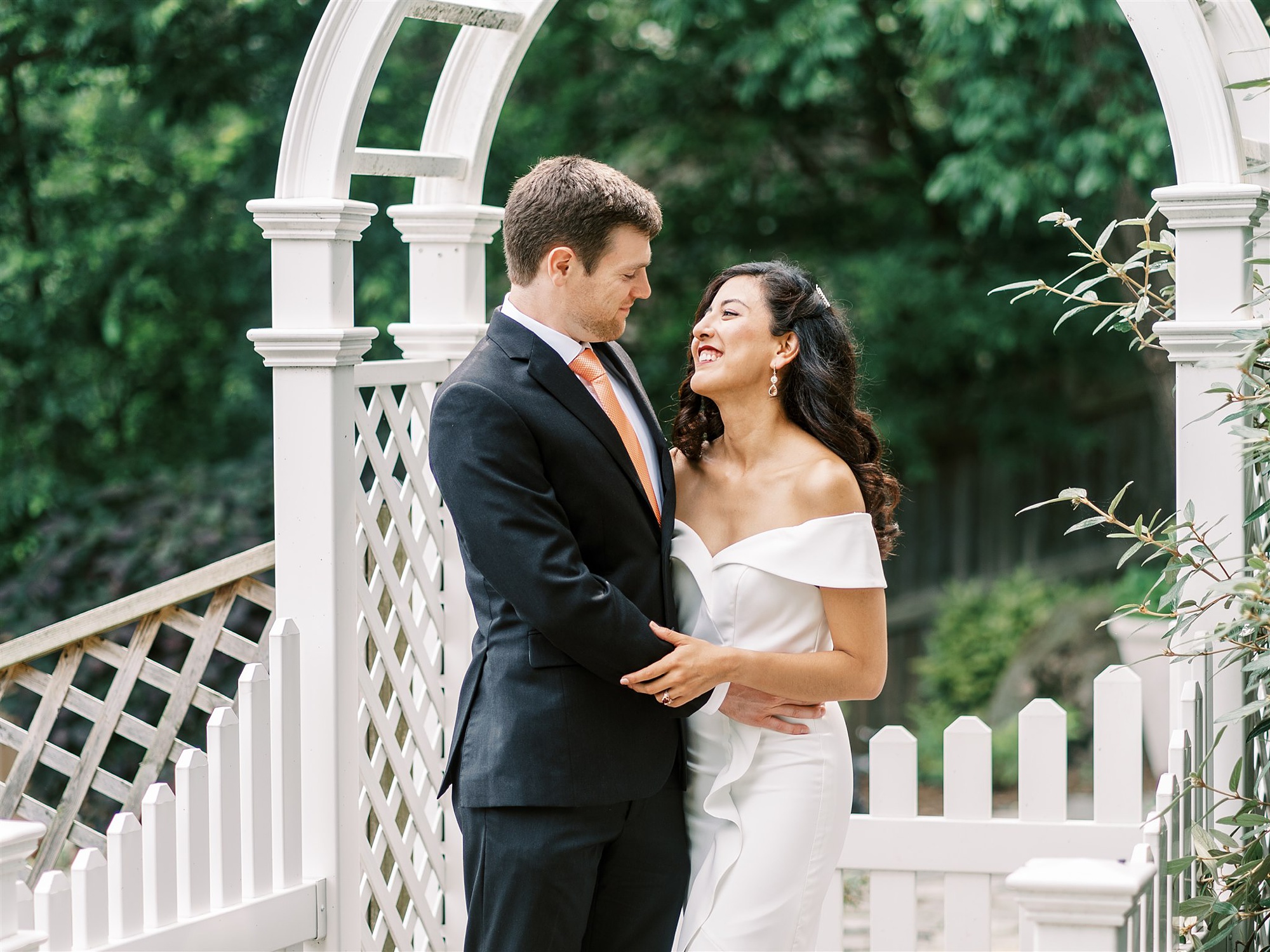 bride and groom smile under arbor in backyard