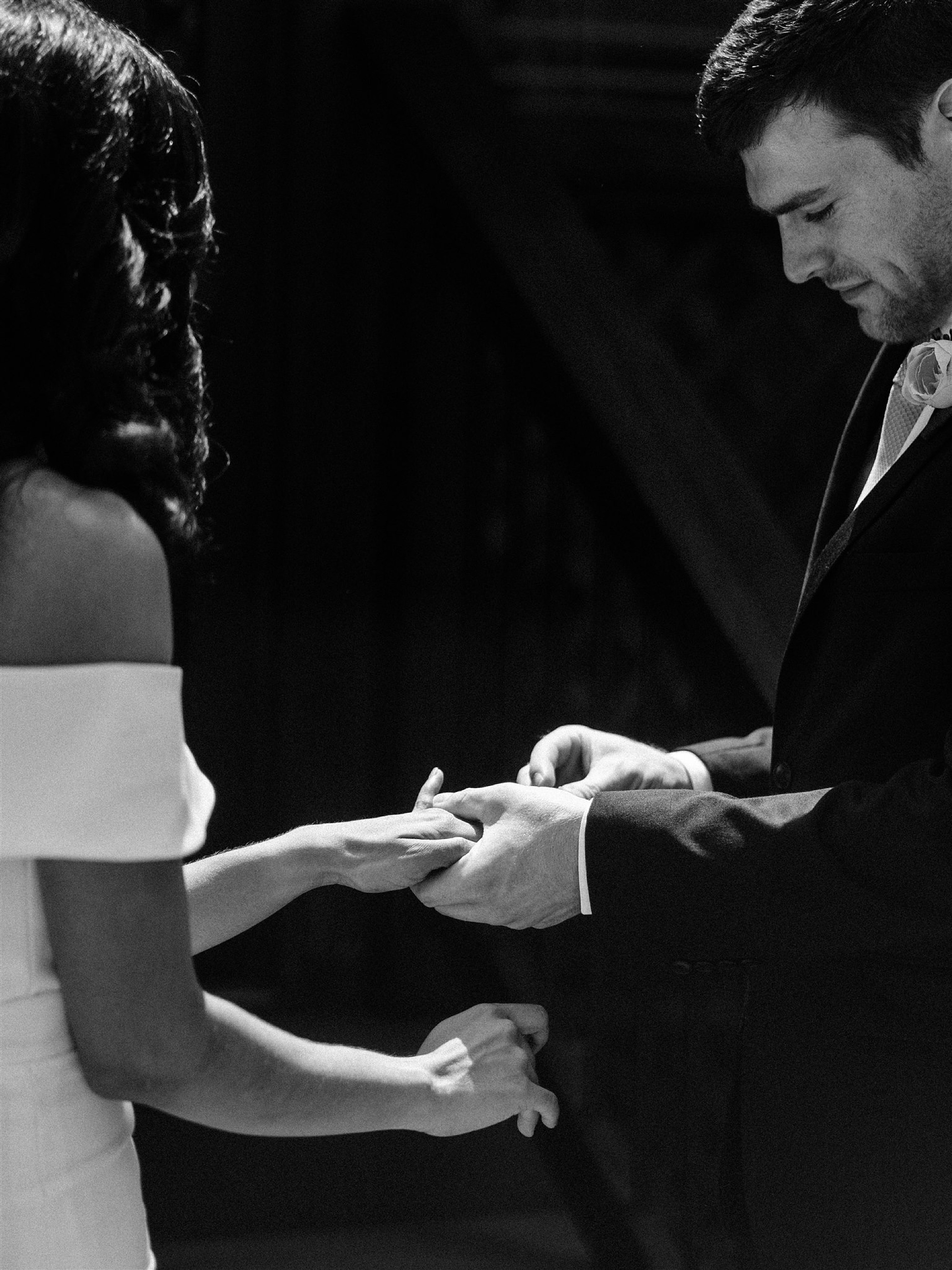 groom slides wedding ring on bride's finger during backyard wedding ceremony 