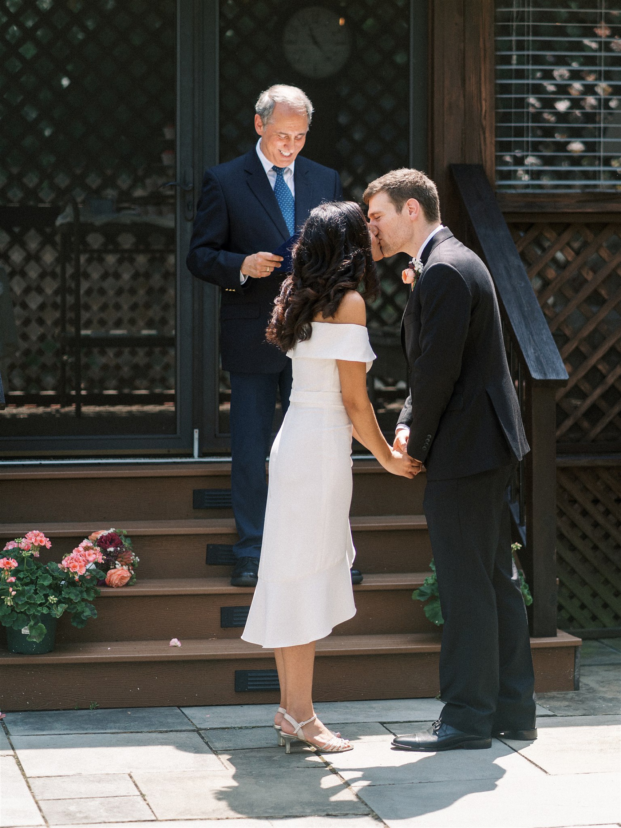 bride and groom kiss during backyard wedding ceremony 