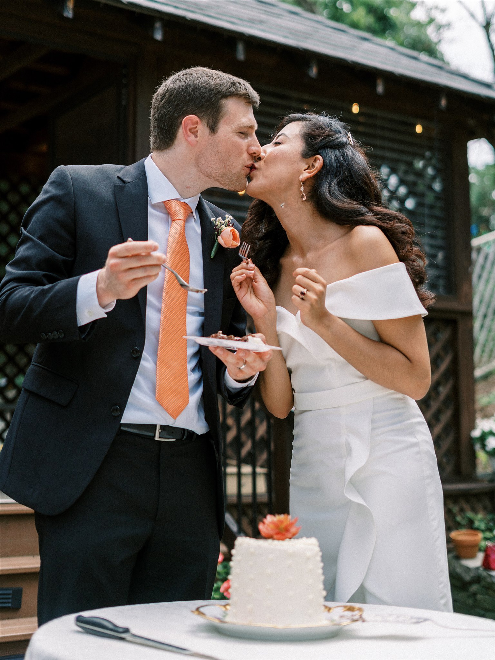 newlyweds kiss after cutting wedding cake in backyard 