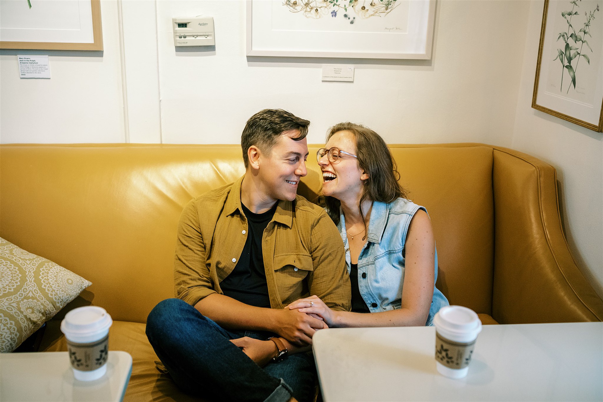 couple laughs on couch at Trinity House Cafe during engagement photos