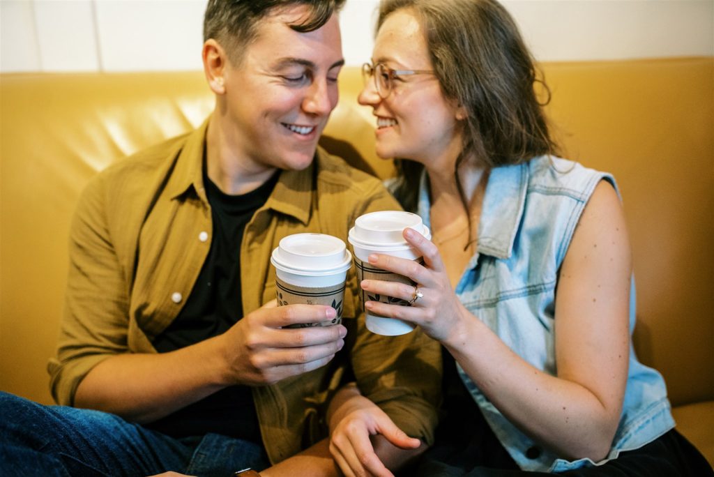 engaged couple toasts coffee mugs during downtown Leesburg engagement session