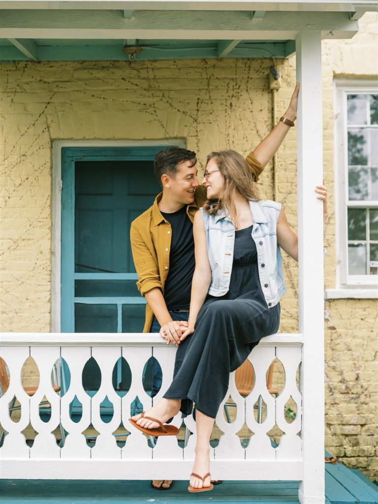 engaged couple sits on porch of house 