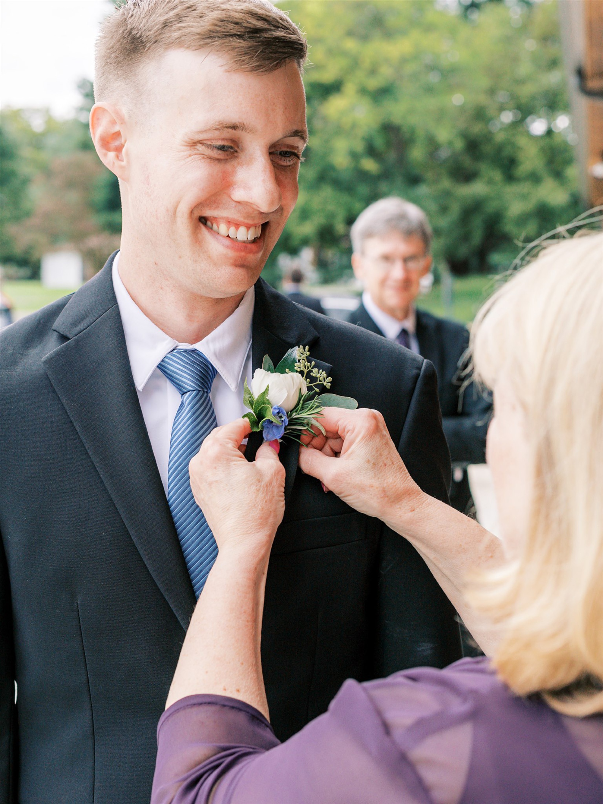 mother of groom pins on boutonniere 