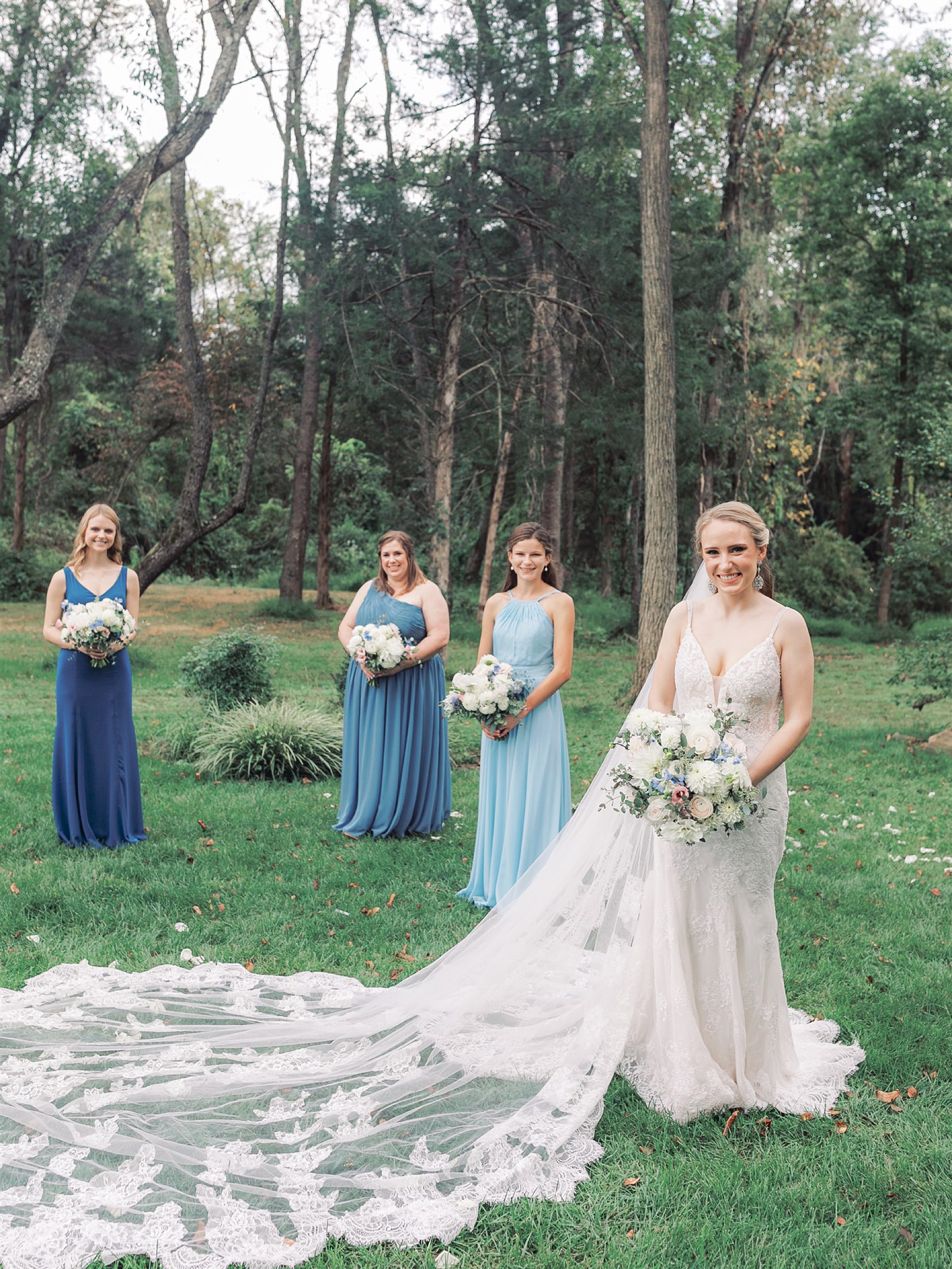 bride poses with bridesmaids in blue gowns