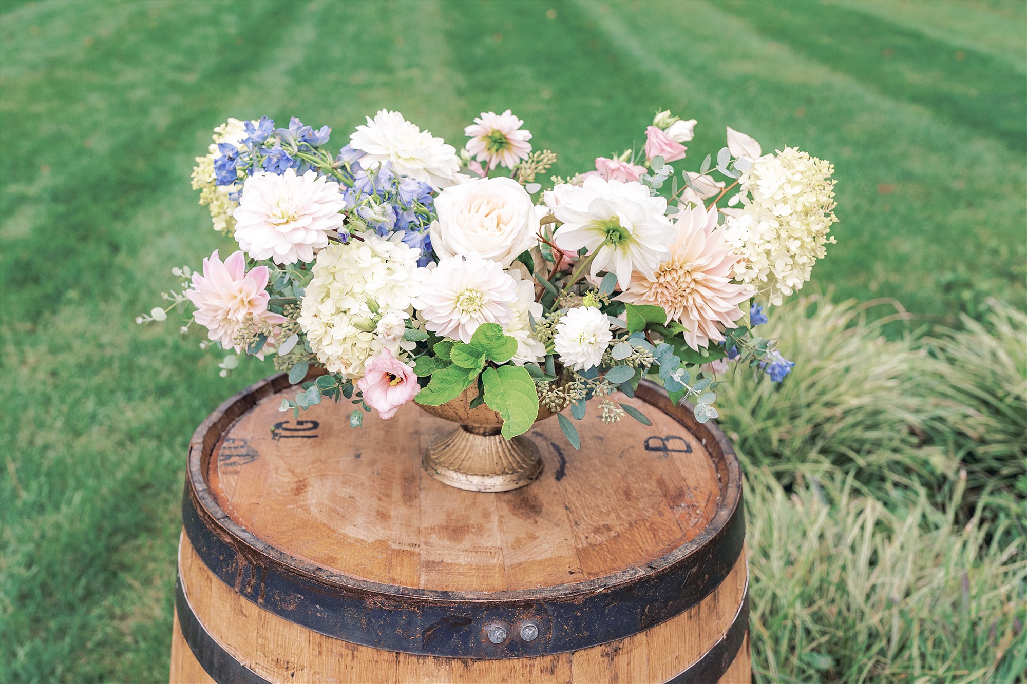 pastel wedding florals sit on barrels at outdoor fall wedding ceremony at Mt Defiance Cidery