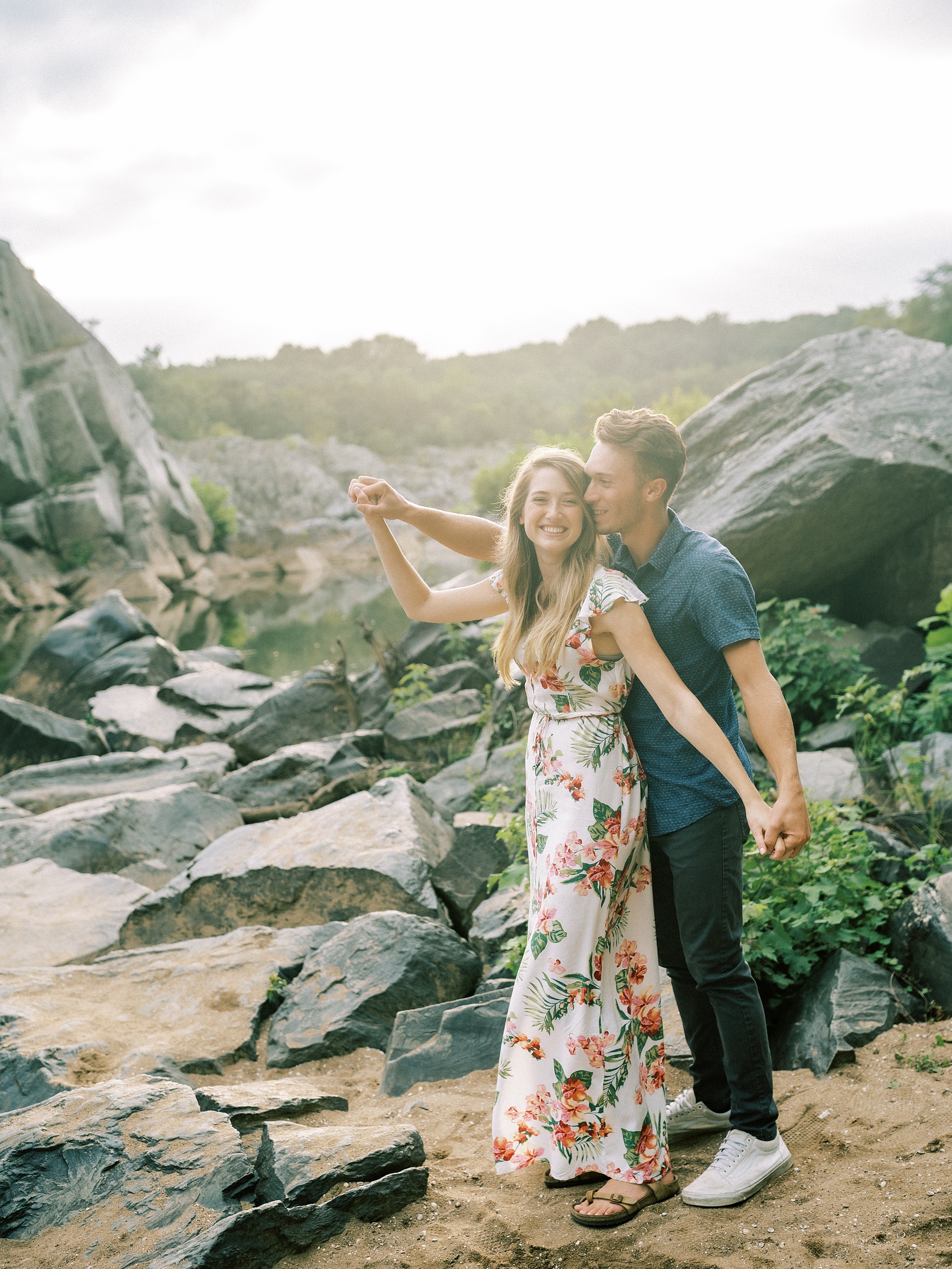 bride and groom stand playfully on rocks at Great Falls Park