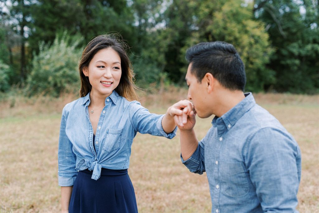 groom kisses fiancees hand during Manassas Battlefield Park engagement photos
