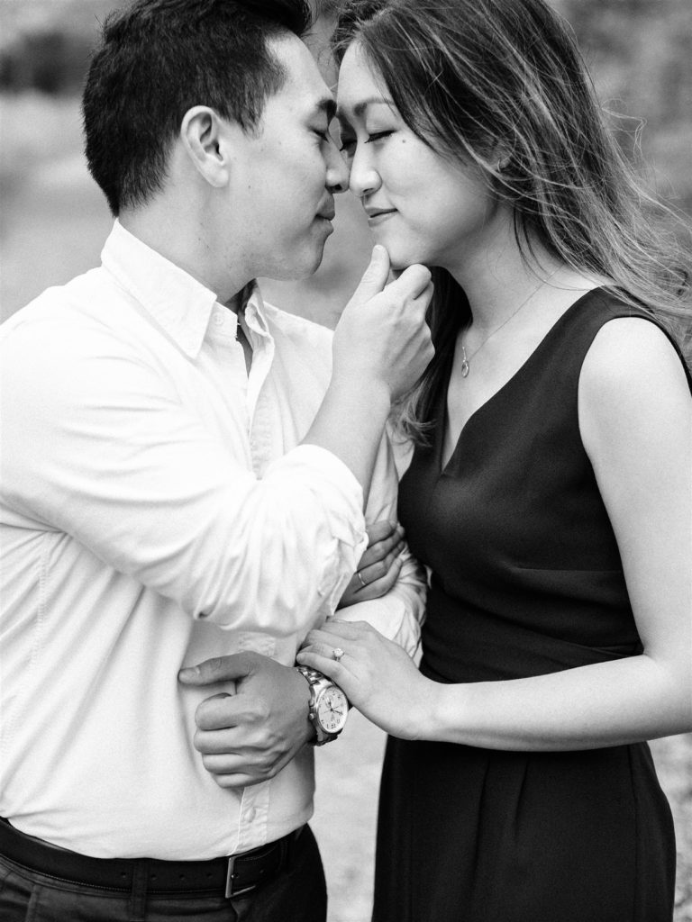 groom holds bride's chin during engagement photos as he goes to kiss her