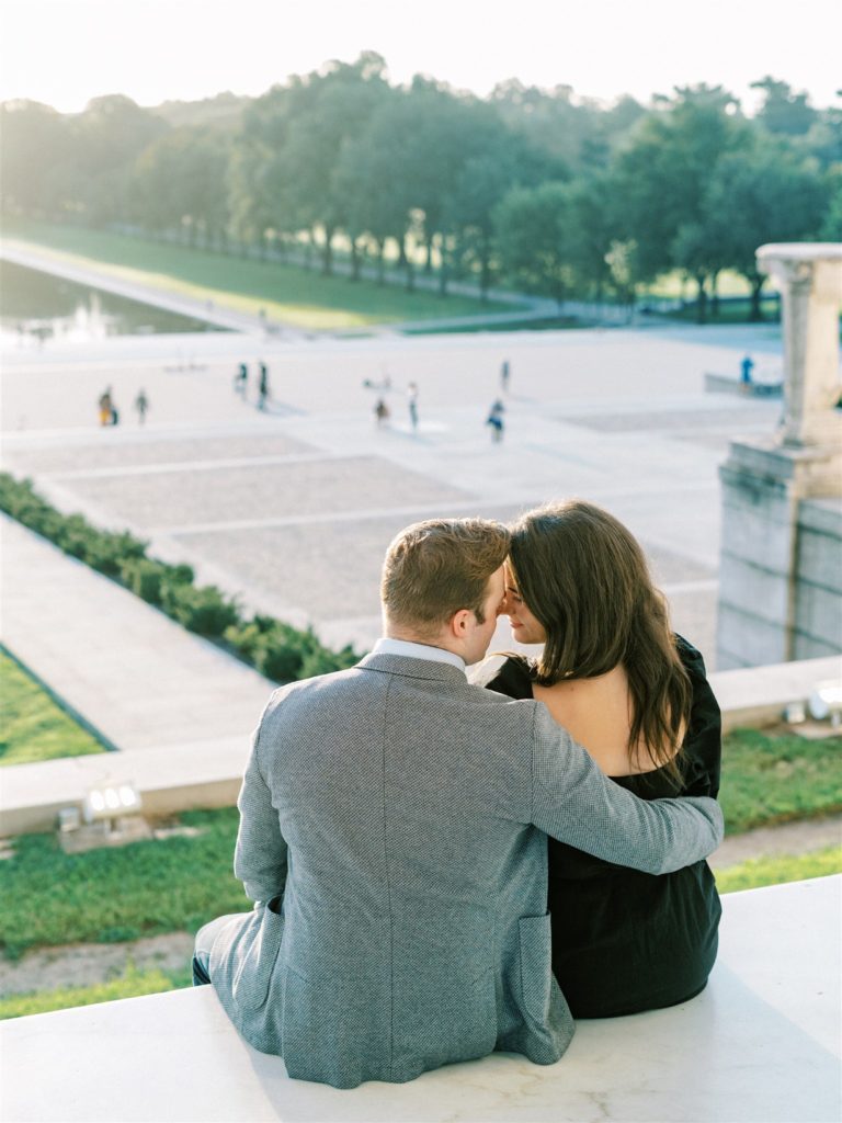 engaged couple sits on Lincoln Memorial overlooking DC