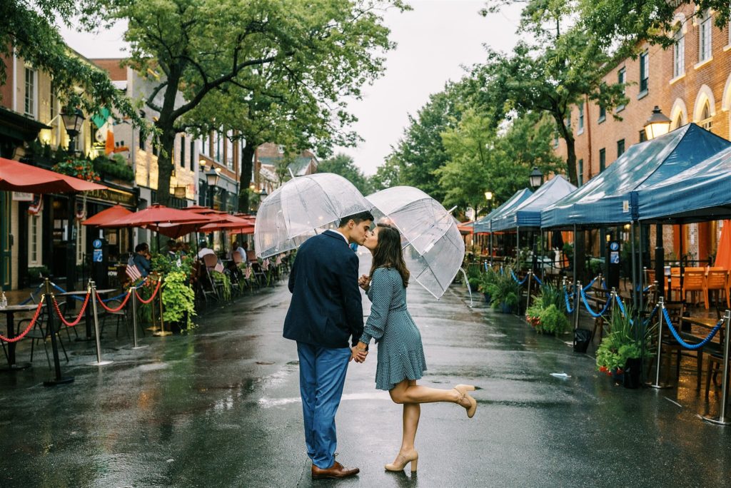 engaged couple kisses under umbrella in Old Town Alexandria