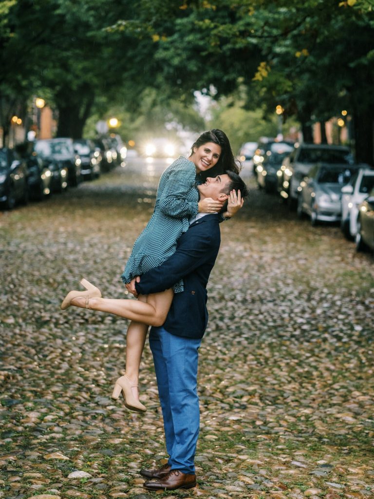 groom lifts bride on cobblestone road in Old Town Alexandria