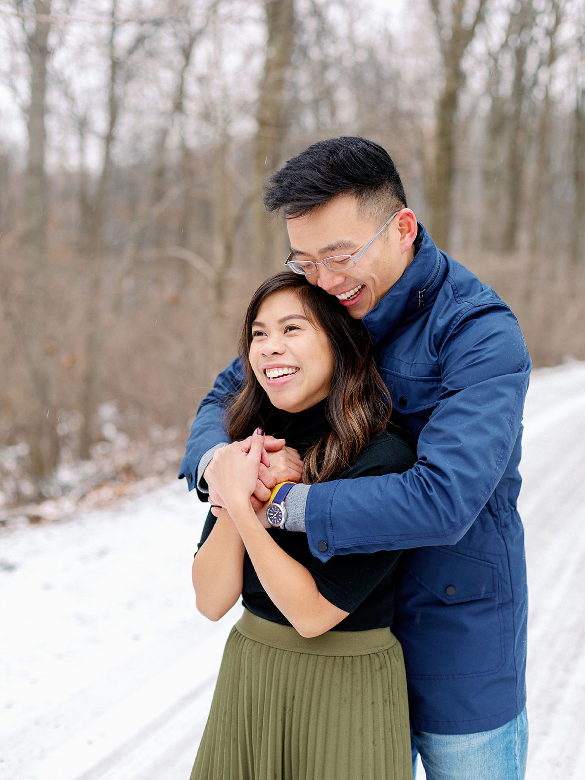 groom hugs bride from behind during Snowy Engagement Session in Bluemont, VA 